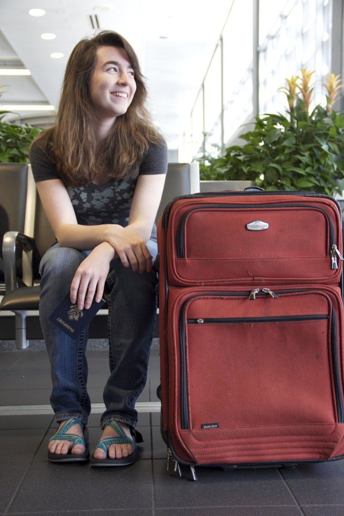 lady sitting in airport with large suitcase. 
